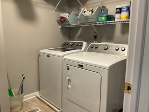 A laundry room with two front-loading washers and dryers, a shelf with cleaning supplies, and a mop holder. - Spacious 3 Bedroom 2 Full baths in Wildwood Crest. 3 Blocks from to the beach. (Wildwood)