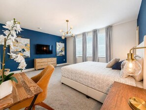 Un dormitorio con cama, televisión, escritorio y silla.
