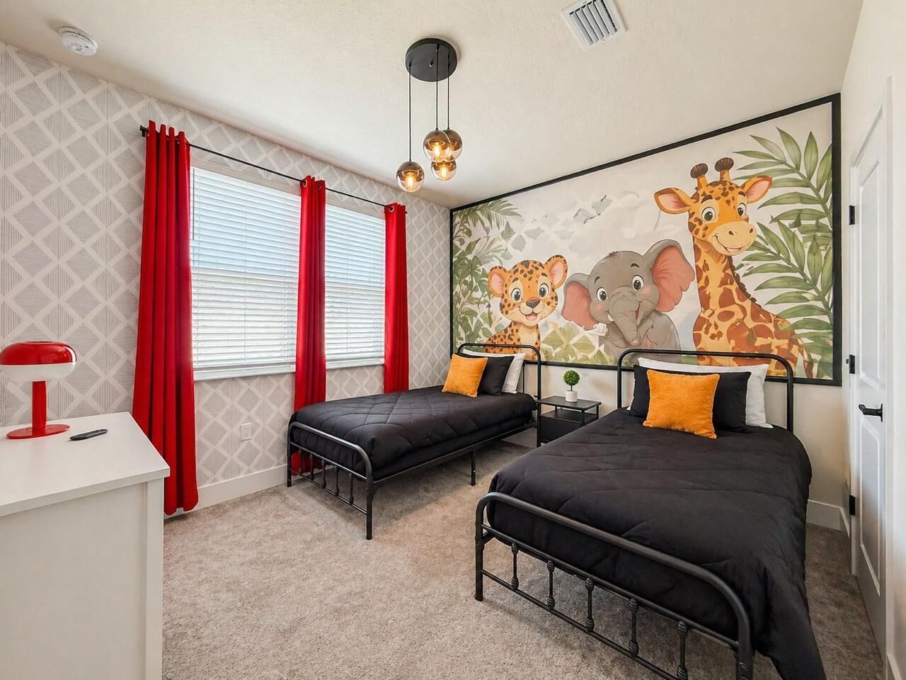 A bedroom with two single beds, a desk, a red lamp, and a large giraffe-themed wall mural.