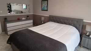 Et soveværelse med seng, kommode, spejl, kunst og et natbord.