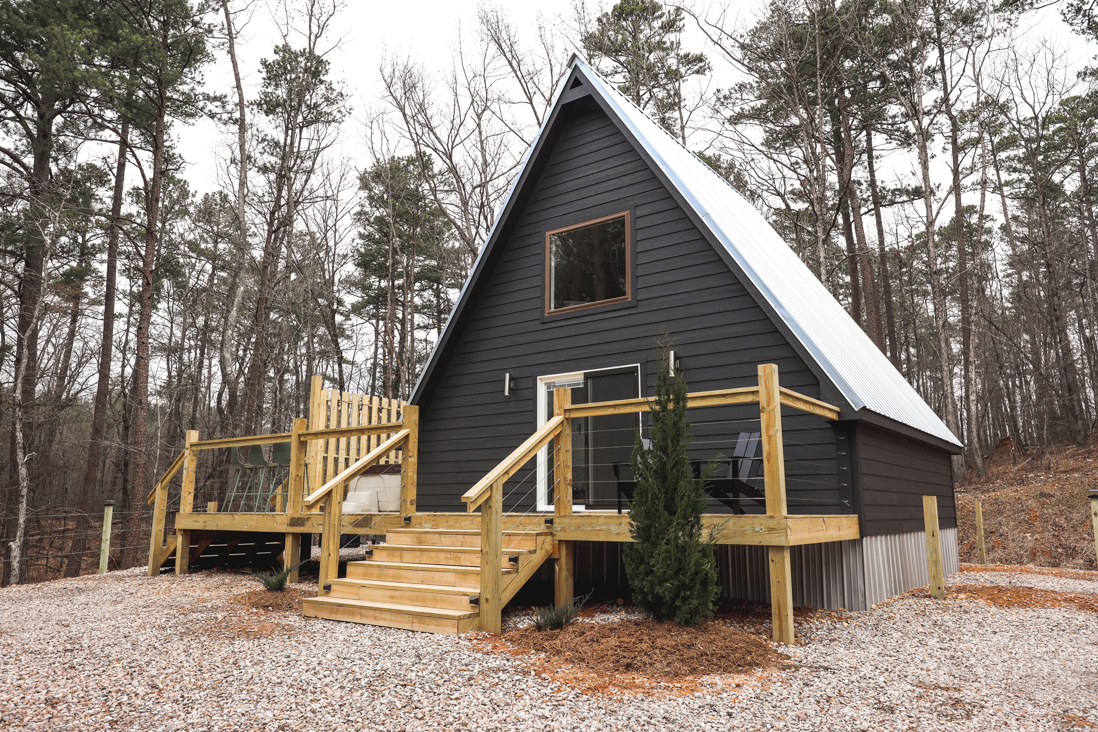 A cabin with a wooden deck and stairs leading to a covered porch.