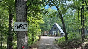 ”OUACHITA CABIN” -niminen mökki sijaitsee metsän keskellä, ja mökille johtaa sorapolkua.