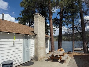 Eine Holzhütte mit Schornstein, Holzfassade und einem Picknicktisch am See.