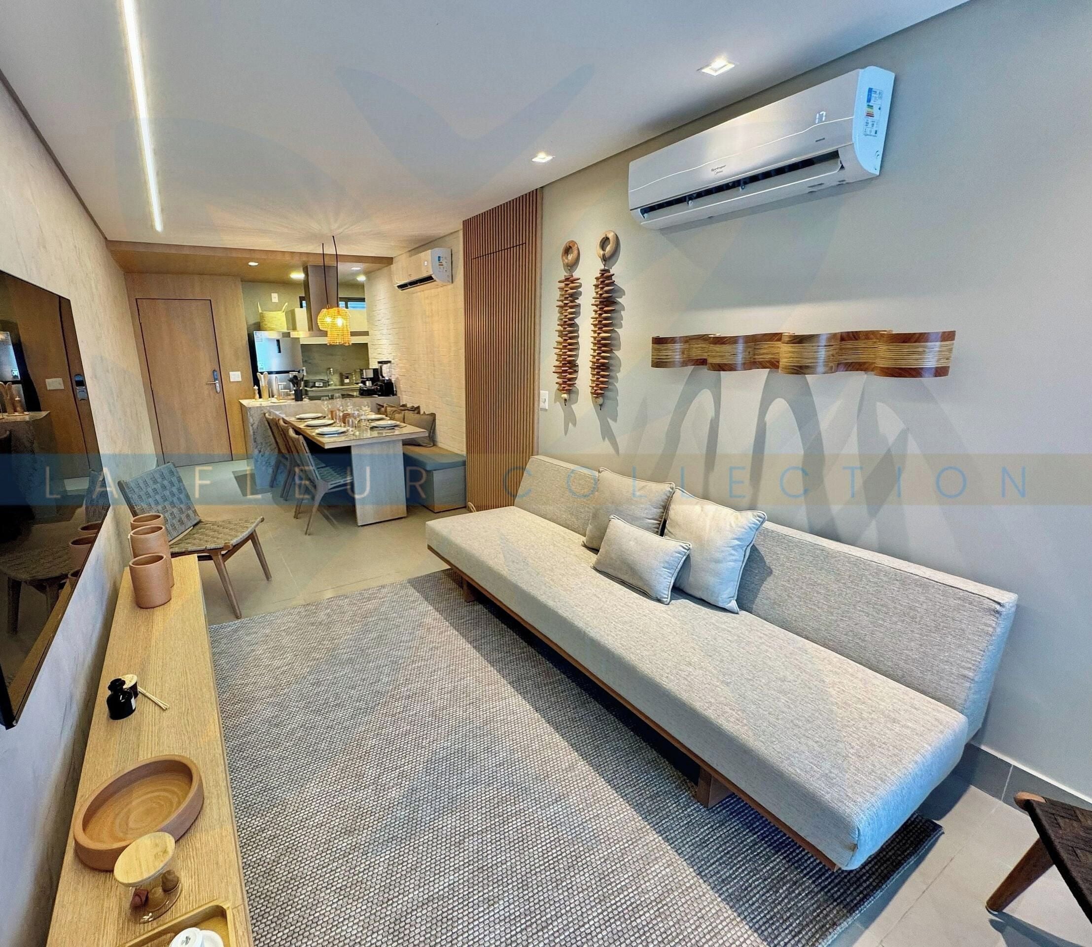 A modern living room with a sofa, a dining area, and a kitchen in the background.