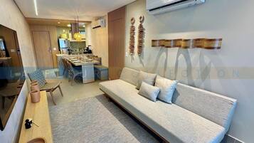 A modern living room with a sofa, a dining area, and a kitchen in the background.