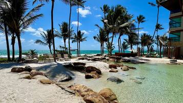 Na praia, areia branca, espreguiçadeiras, guarda-sóis