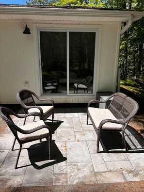 A patio with wicker furniture and a sliding glass door leading to a covered area.
