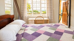Quarto com cama, escrivaninha e vista para o exterior.