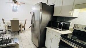 Une cuisine équipée d’un réfrigérateur, d’un four à micro-ondes, d’une cuisinière et d’une table à manger avec des chaises.