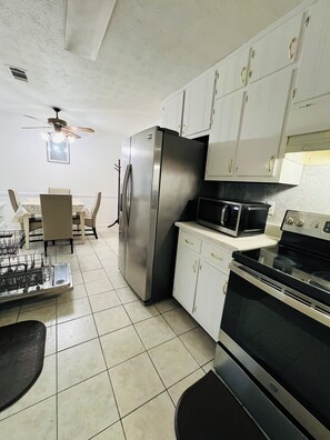 A kitchen with a refrigerator, microwave, stove, and dining table with chairs.