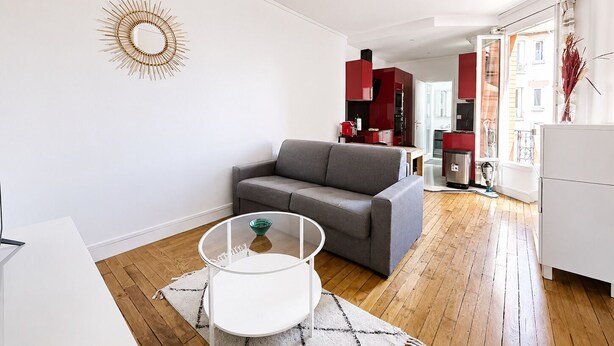 Ein modernes Wohnzimmer mit einem grauen Sofa, einem Glastisch und einer weißen Wanddekoration im Sonnenstrahl-Design.