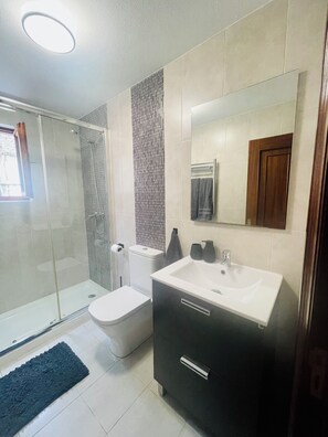 Une salle de bain moderne avec une douche à parois de verre, des toilettes, un lavabo et un grand miroir.