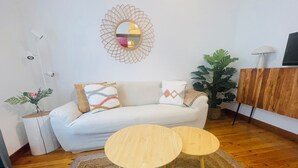A living room with a sofa, two round wooden tables, a decorative mirror, a potted plant, and a television. - Apartment San francisco Oviedo (Oviedo)