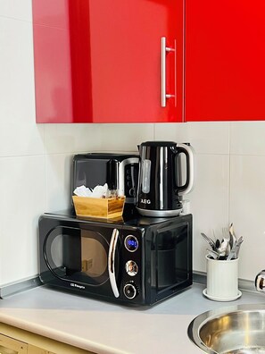 Une cuisine équipée d’un four à micro-ondes, d’une machine à café et d’ustensiles de cuisine.
