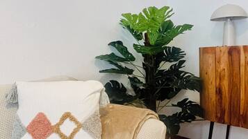 Un salon avec un canapé, une plante en pot, une lampe et un meuble en bois.