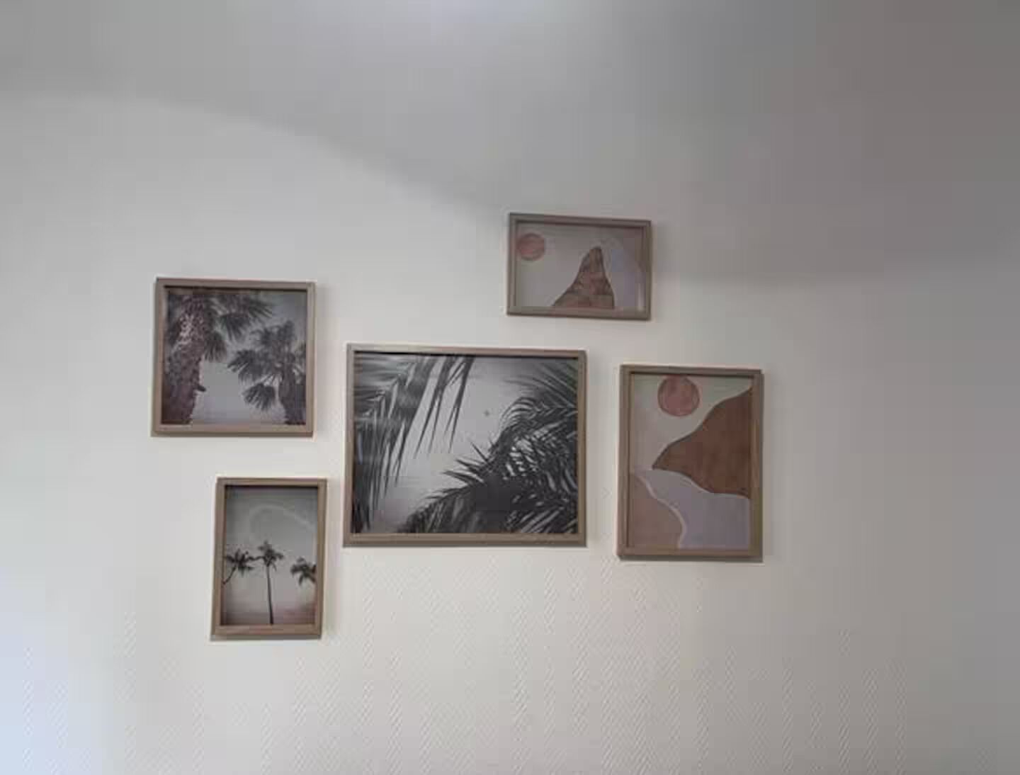 Four framed artworks on a plain wall.