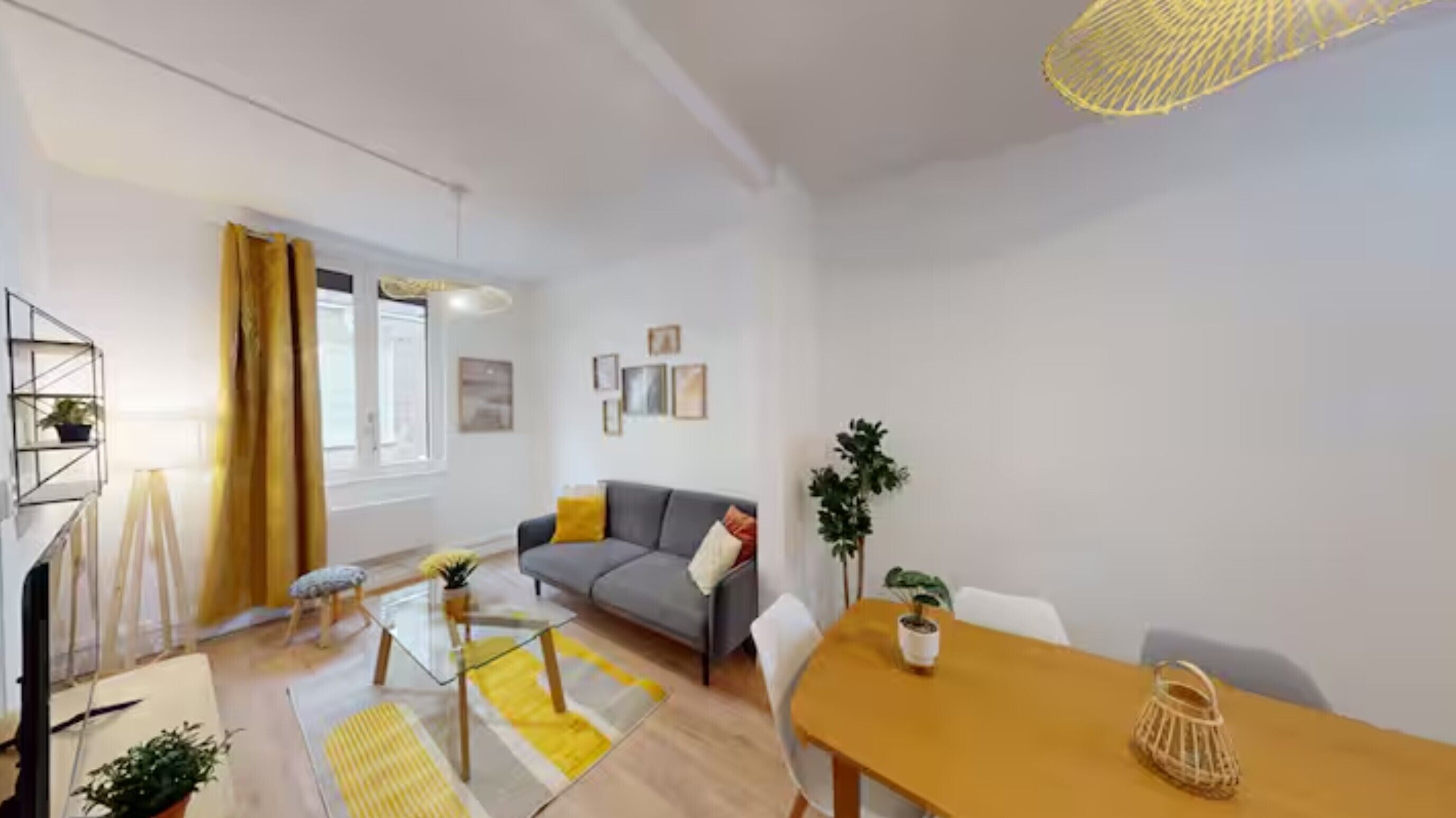 Uma sala de estar moderna com um sofá, uma mesa de centro de vidro e uma mesa de jantar com cadeiras.