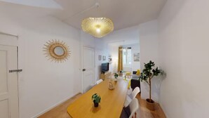 A modern living room with a dining table, a TV, and a large plant.