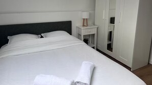 A neatly made bed with white linens, a bedside lamp, and a wardrobe with mirrored doors.
