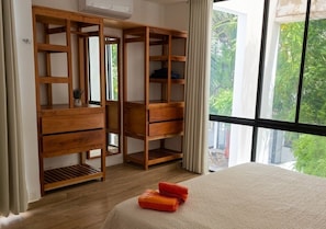 A bedroom with a bed, wooden wardrobe, and a window with a view of greenery. - Telchac 3 Bedrooms + pool and beach (Mérida)