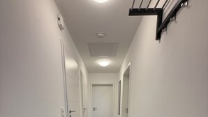 A hallway with a bench, white walls, and a wooden floor.