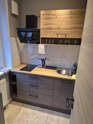 Een compacte keuken met een inbouwfornuis, een spoelbak en een houten bovenkast.