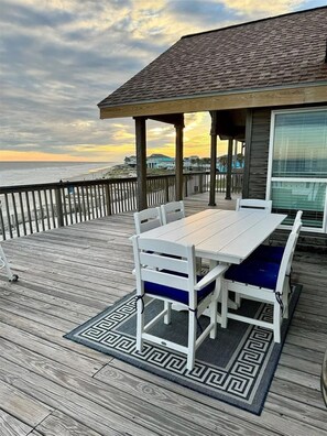 A wooden deck with a table and chairs, overlooking the ocean. - Beach Front - The Hamptons at Spanish Grant (Galveston)