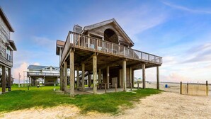 Eine Holzkonstruktion mit Balkon, überdachter Veranda und Blick auf den Strand.
