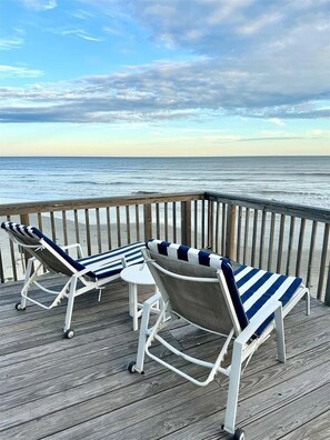 A wooden deck with two lounge chairs and a small table, overlooking the ocean. - Beach Front - The Hamptons at Spanish Grant (Galveston)