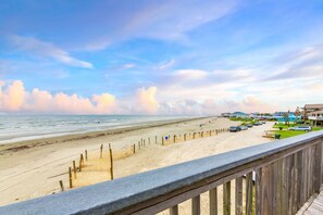A beach view with a wooden fence, beach chairs, and a row of houses. - Beach Front - The Hamptons at Spanish Grant (Galveston)