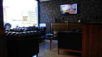 Una sala de estar moderna con un sofá de cuero, una mesa de centro y un televisor de pantalla plana montado en una pared con textura.