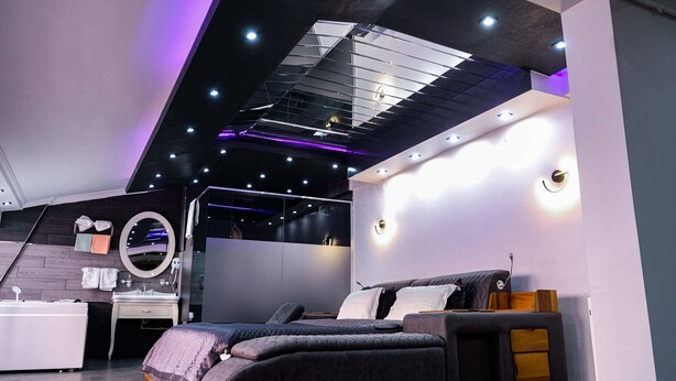 Un dormitorio moderno con cama, mesita de noche y espejo.