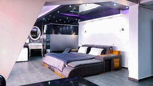 Un dormitorio moderno con cama, mesitas de noche, escritorio y espejo.