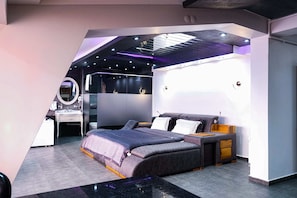 Un dormitorio moderno con cama, mesitas de noche, escritorio y espejo.