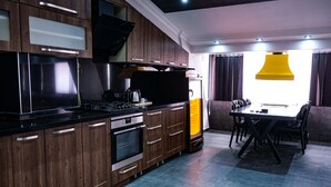 Una cocina moderna con armarios de madera, encimera negra y una zona de comedor con mesa y sillas.