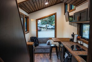 Cocina compacta con encimeras de madera, estufa integrada y ventana con vista a un estacionamiento.