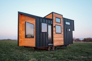 Una casa moderna y compacta con techo plano, ventanas grandes y fachada de madera.