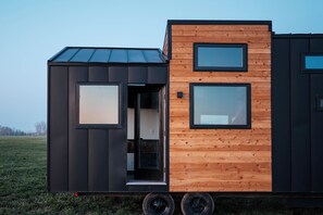A modern mobile home with a black exterior, wooden accents, and large windows. - Cozy 1-bedroom cabin in soothing Island Park next to Hank the painted stallion (Island Park)