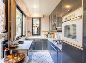 A compact kitchen with a central island, built-in appliances, and a view through a window. - Quiet town house with garden in the heart of Agen (Agen)