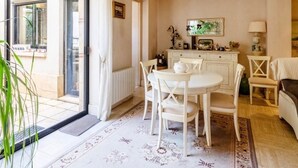Spiseområde med et bord, stole, en radiator, et skab og et vindue med gardiner.