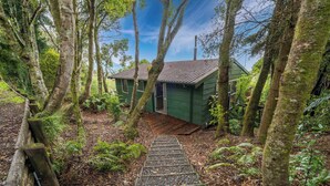 Een houten trap die leidt naar een groen gebouw, omringd door bomen.