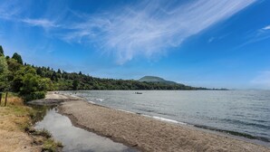 Een strand met een heldere lucht, rustig water en een heuvel in de verte.