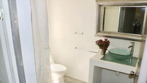 Et badeværelse med en vask af glas, et hvidt toilet og et spejl med dekorativ ramme.