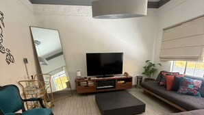 En stue med sofa, stol, fjernsyn og bogreol.
