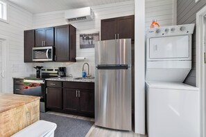 Una cocina compacta con armarios oscuros, un refrigerador de acero inoxidable, un microondas y un lavavajillas.