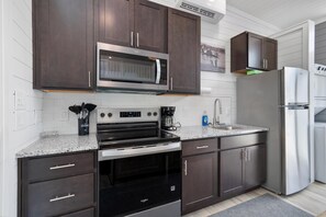 Une cuisine moderne avec des meubles en bois foncé, des appareils électroménagers en acier inoxydable et un plan de travail en granit.
