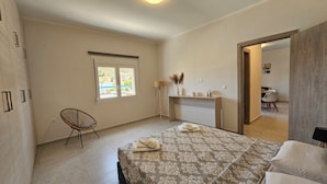 Ein Schlafzimmer mit Bett, Stuhl, Schreibtisch, Lampe und Fenster.