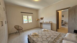 Ein Schlafzimmer mit Bett, Stuhl, Schreibtisch, Lampe und Fenster.