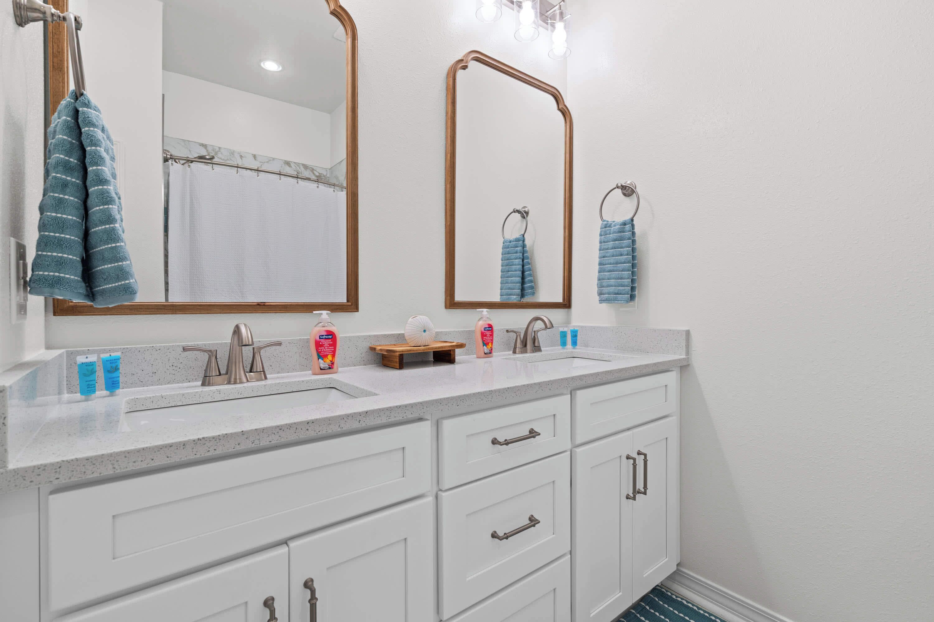 Une salle de bain avec deux lavabos, un miroir et un porte-serviettes.