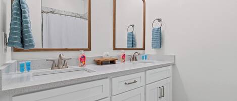 Une salle de bain avec deux lavabos, un miroir et un porte-serviettes.